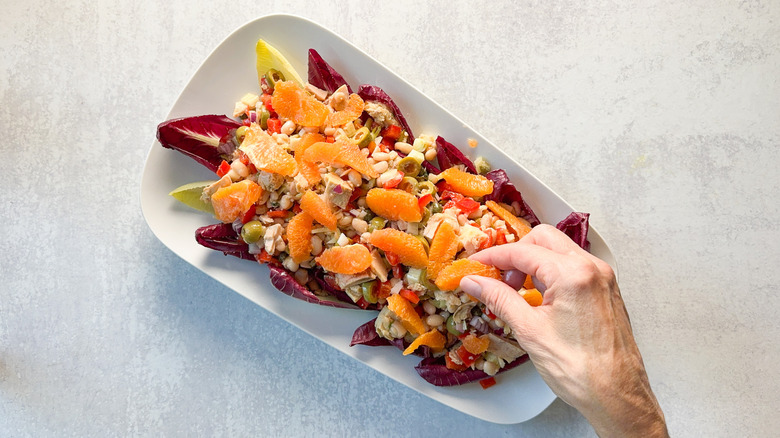 Adding orange segments to Spanish-inspired tuna salad on platter