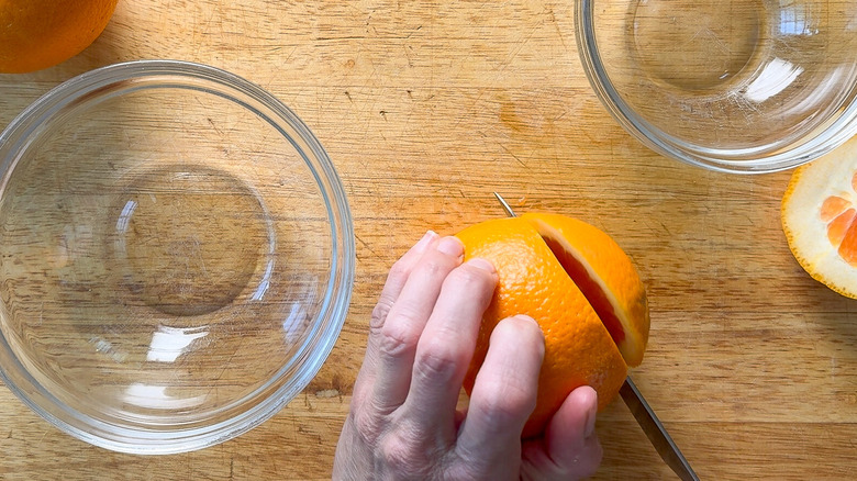 Cutting the ends off of navel oranges on cutting board with bowls