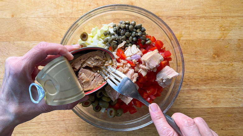 Spanish-inspired tuna salad ingredients with open can of tuna in glass bowl