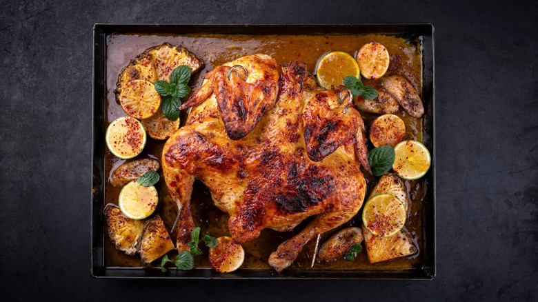 Spatchcocked chicken on a sheet pan with fruits