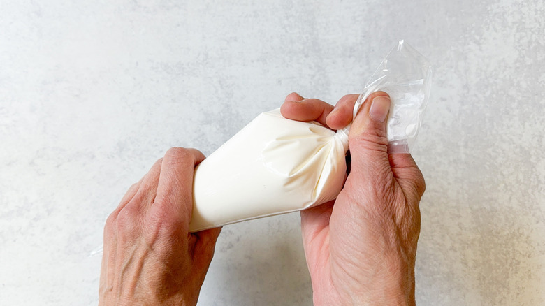 Sour cream in a disposable plastic pastry bag twisted closed