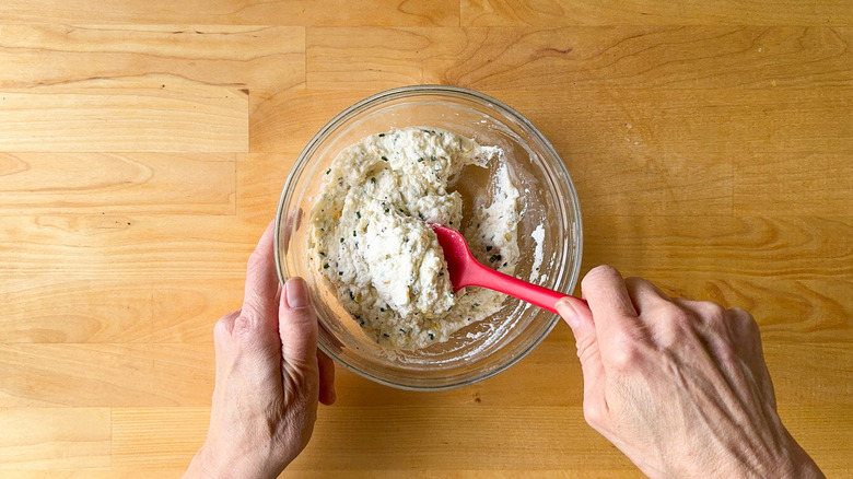 Mixing lemon ricotta filling in glass bowl with rubber spatula