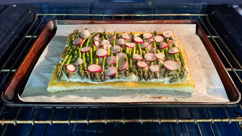 Springy asparagus and lemon ricotta tart baking in oven on baking sheet