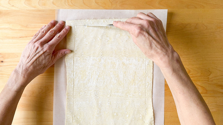 Scoring a border around the edges of puff pastry using a small knife