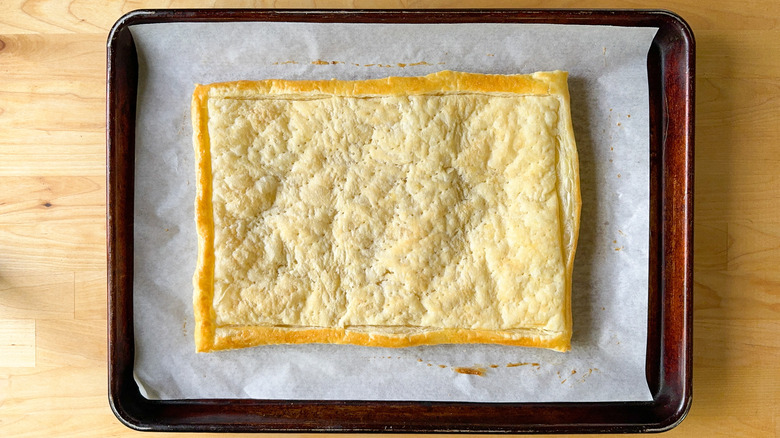 Baked puff pastry on parchment paper cooling on baking sheet