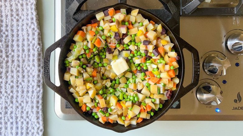 Springy vegetarian pot pie vegetables and butter in cast iron skillet on stove top