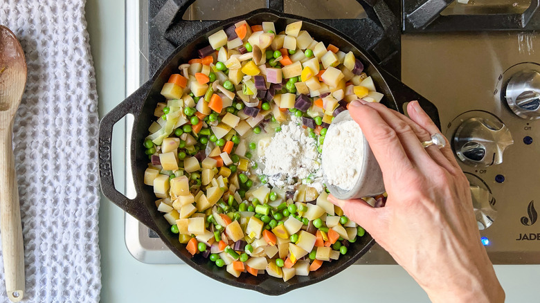 Adding flour to springy vegetarian pot pie vegetables and butter on stove top