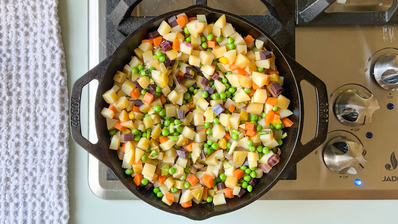 Vegetables for springy vegetarian pot pie in cast iron pan on stovetop