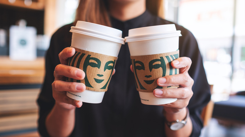 Woman holding two Starbucks hot drink cups