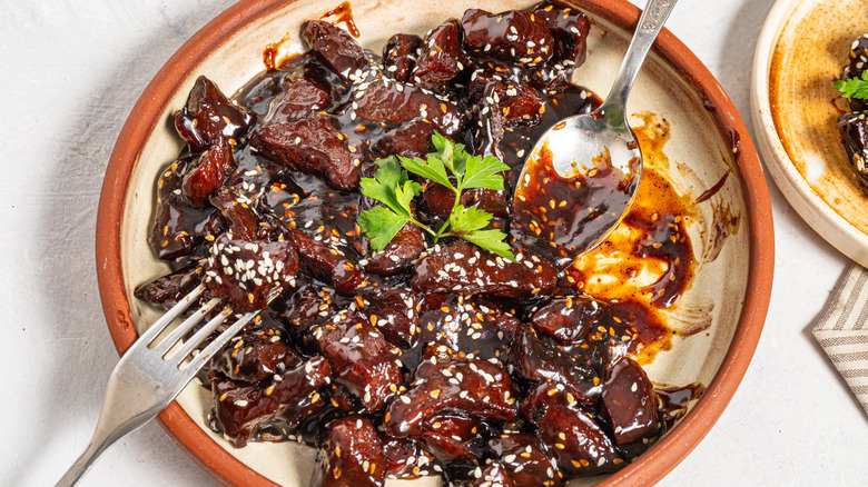 Sticky soy steak bites on a plate with fork and spoon in it