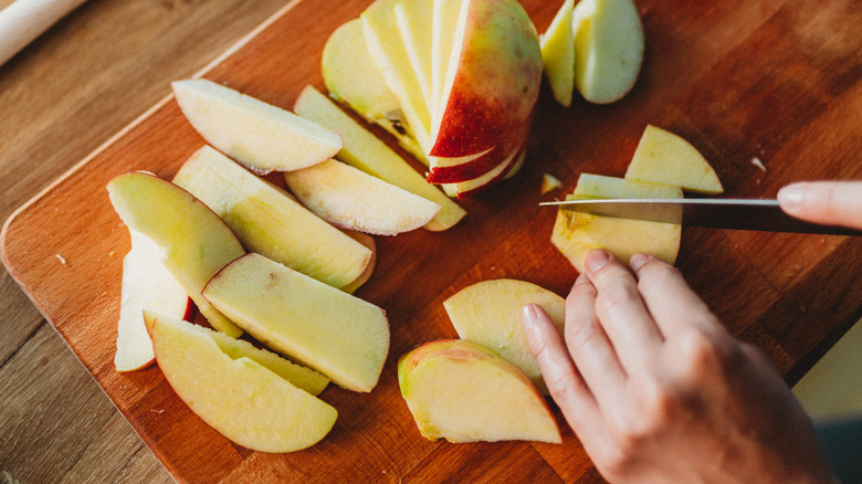 Slicing an apple on wooden cutting board