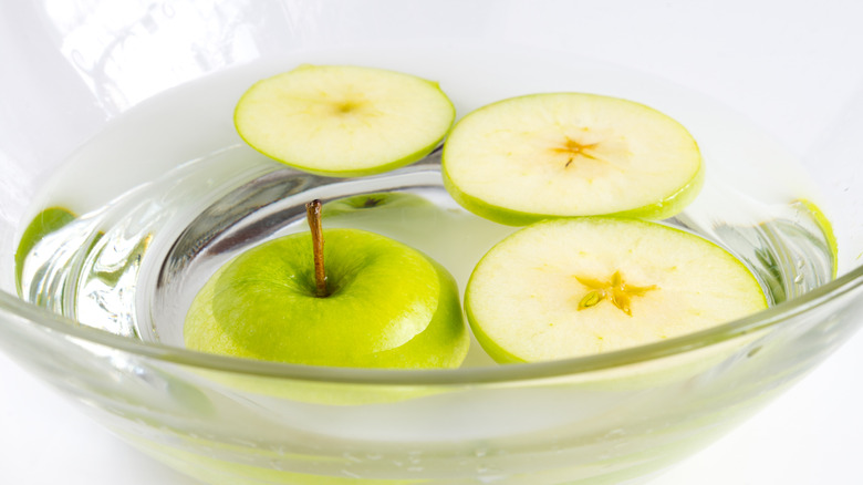 Sliced green apples in a bowl of water