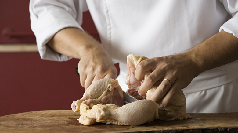 Chef cutting raw chicken