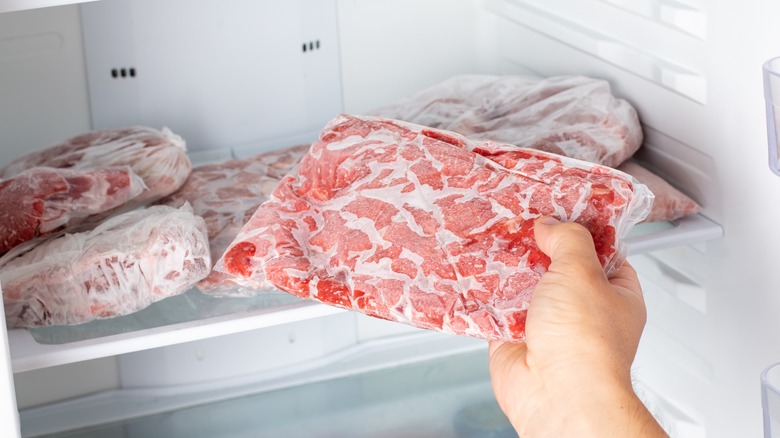 Hand pulling meat from freezer