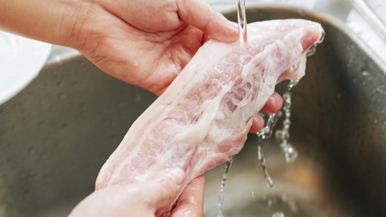 Rinsing bacon under faucet