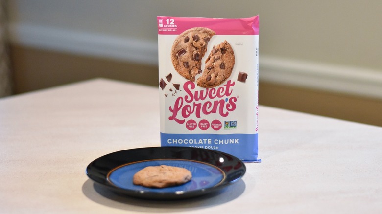 A package of Sweet Loren's chocolate chunk cookie dough with a baked cookie on a blue and black plate