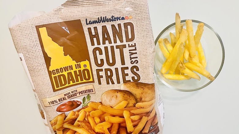 Bag of frozen Grown In Idaho Hand Cut Style Fries with dish of cooked ones alongside