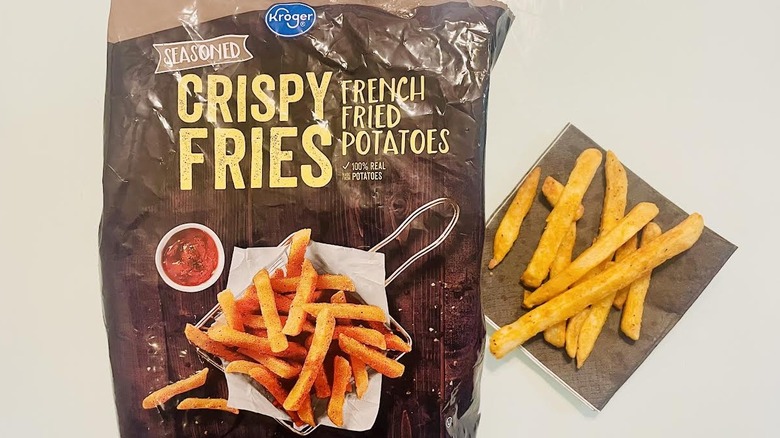 Bag of frozen Kroger Seasoned Crispy Fries with pile of cooked ones on napkin