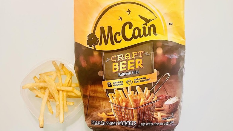 Bag of frozen McCain Craft Beer Battered Fries with small container of cooked ones