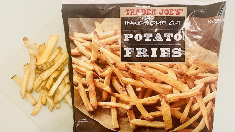 Bag of frozen Trader Joe's Handsome Cut Fries with pile of cooked ones alongside