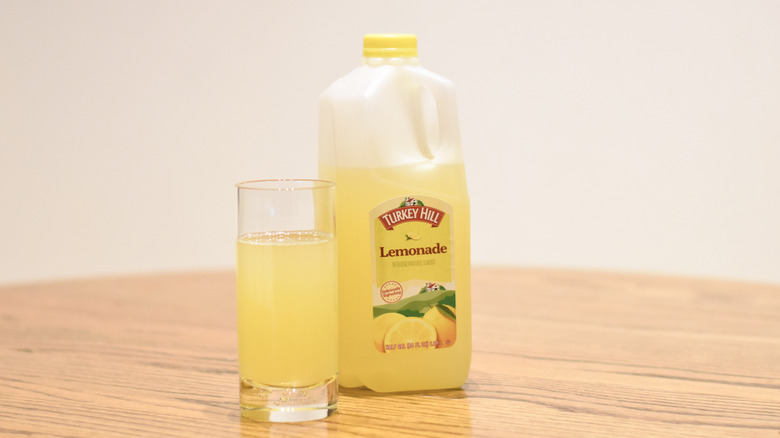 A jug of Turkey Hill lemonade next to a glass of lemonade on a wooden table