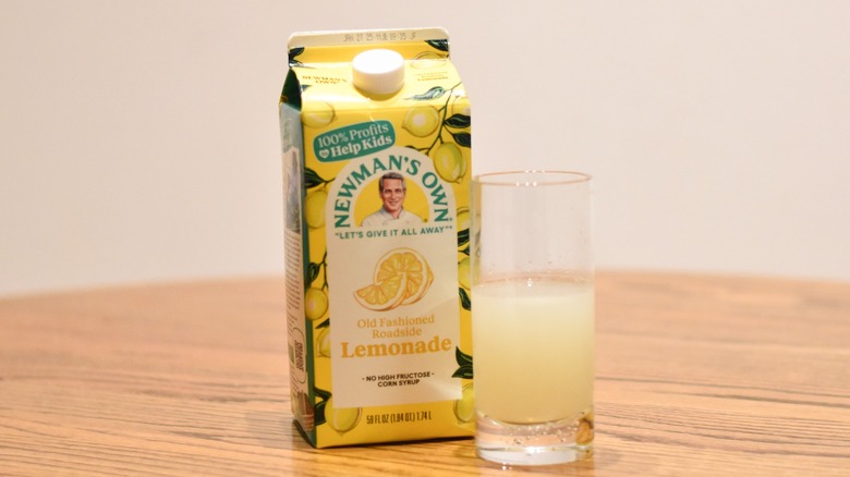 A carton of Newman's Own lemonade next to a glass of lemonade