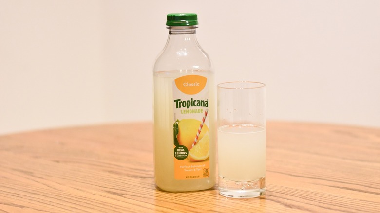 A bottle of Tropicana lemonade next to a glass of lemonade