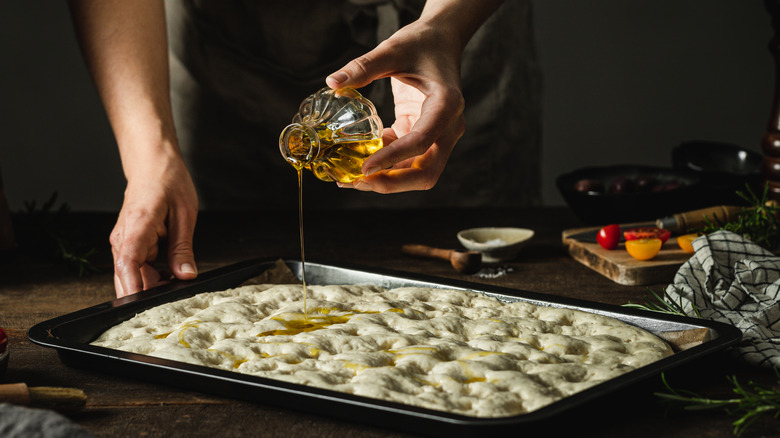 Pouring oil over focaccia dough