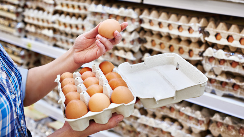 a shopper inspects a carton of eggs at the supermarket