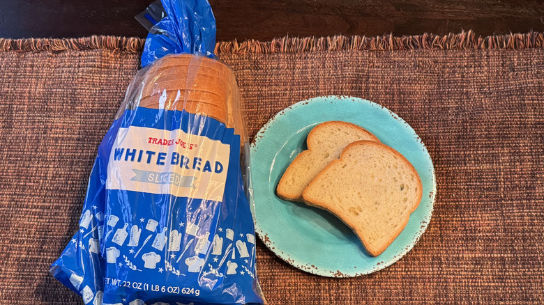 A loaf of Trader Joe's White Bread and two slices on a blue plate