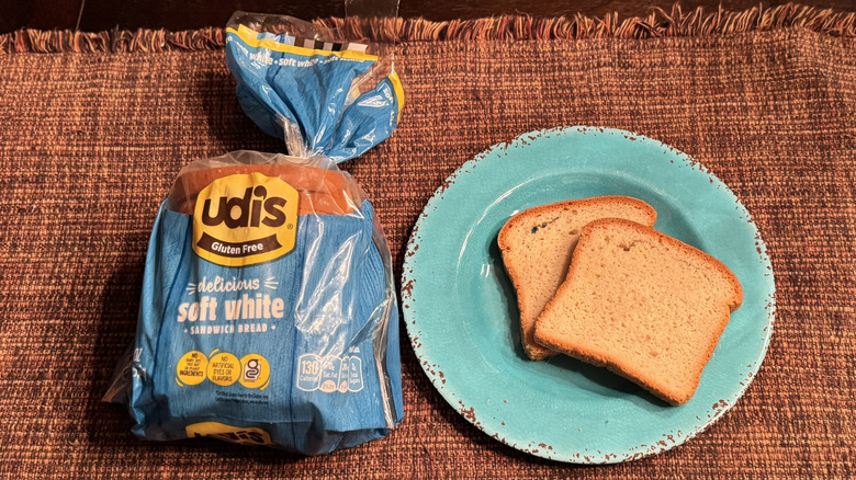 A loaf of Udi's bread and two slices sitting on a blue plate