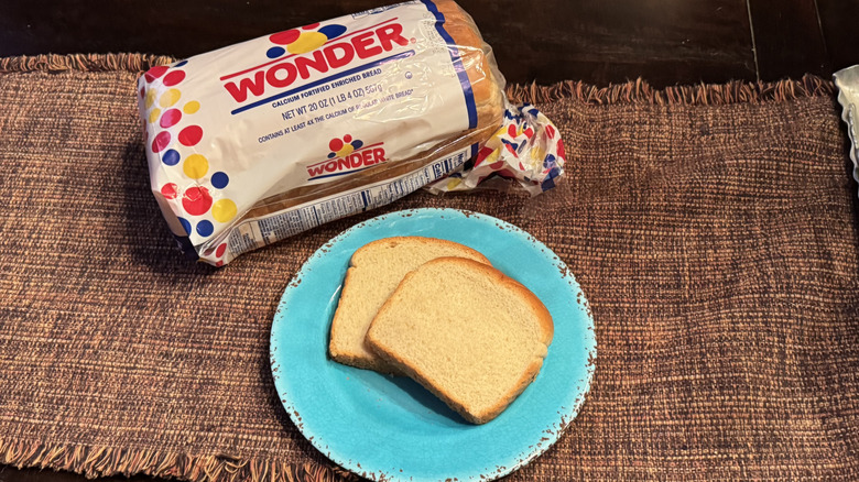 A loaf of Wonder Bread and two slices on a blue plate