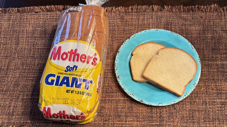 A loaf of Mother's Giant White Bread and two slices on a blue plate