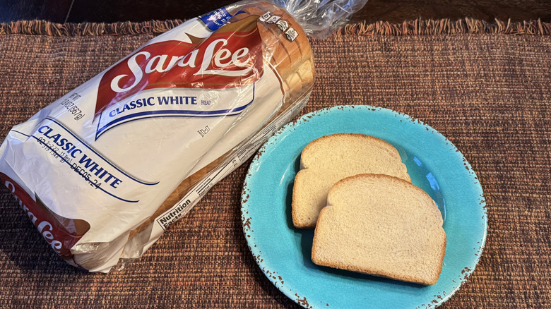 A loaf of Sara Lee Classic White Bread and two slices on a blue plate