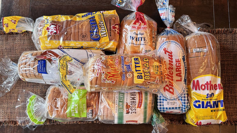 An assortment of store-bought white bread loaves sitting on a table