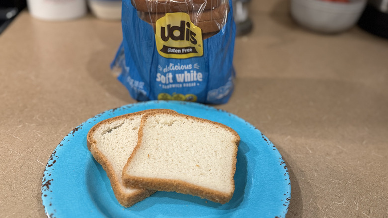 Udi's white bread on a kitchen counter with two slices sitting on a plate