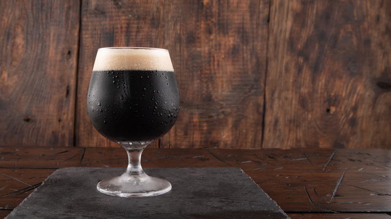 Stout beer in goblet on slate and wooden table