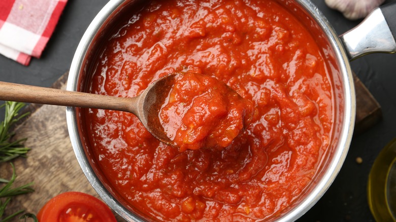 a silver pot of tomato sauce with a wooden spoon