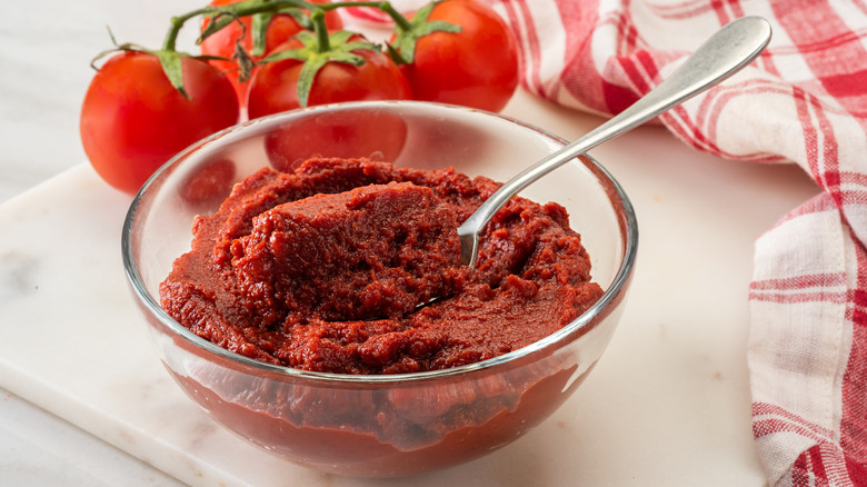 a clear bowl filled with tomato paste on a cutting board