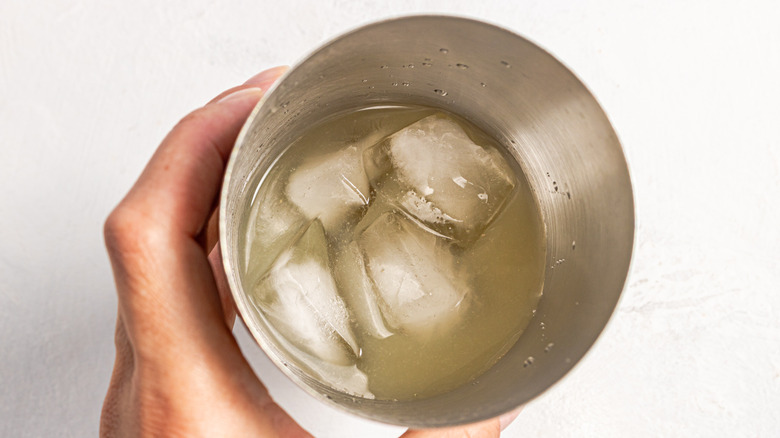 Holding a shaker with ice and liquid in it