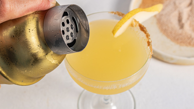 Pouring a drink form a cocktail shaker into a glass