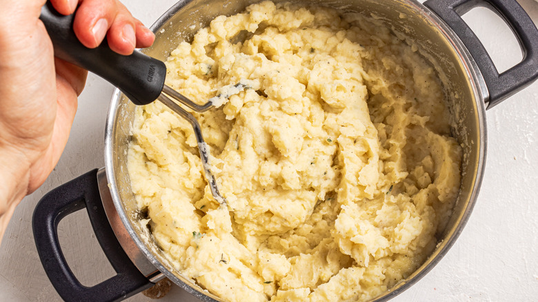 mashing creamy potatoes in pot