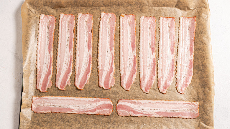 raw bacon slices on sheet