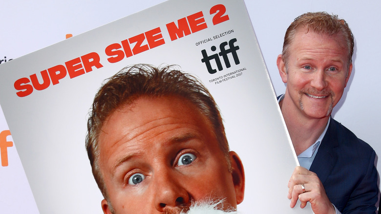 Morgan Spurlock holding a movie poster 