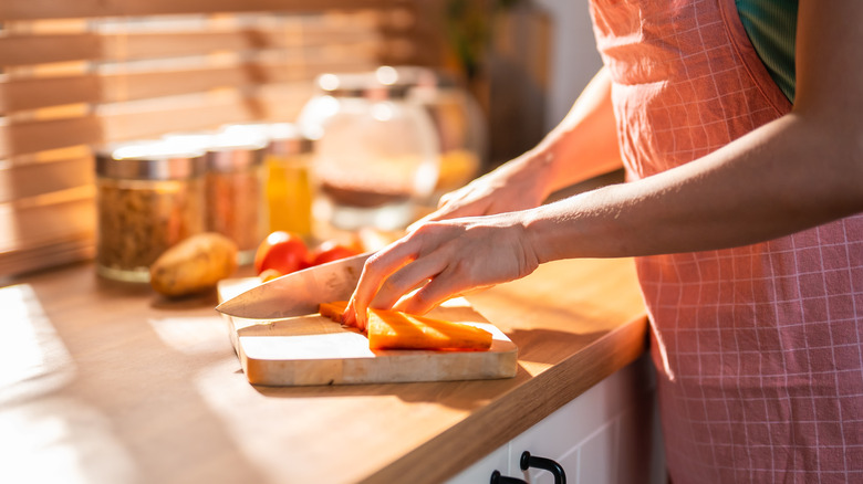 Home cook slicing carrots on cutting board