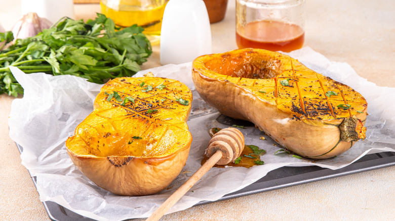 Two halves of baked butternut squash with herbs are displayed.