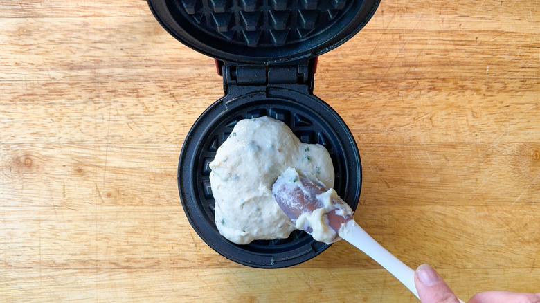 Spreading waffle batter in waffle iron with spatula