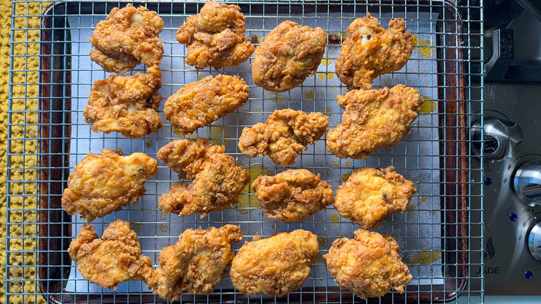 Fried chicken thighs on rack over parchment-lined baking sheet