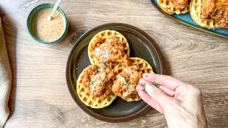 Garnishing sweet and savory crispy buttermilk chicken and waffles with chopped chives