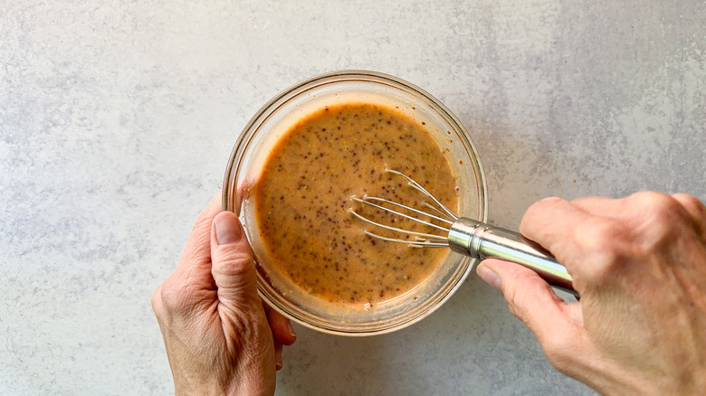 Whisking spicy honey mustard sauce in glass bowl